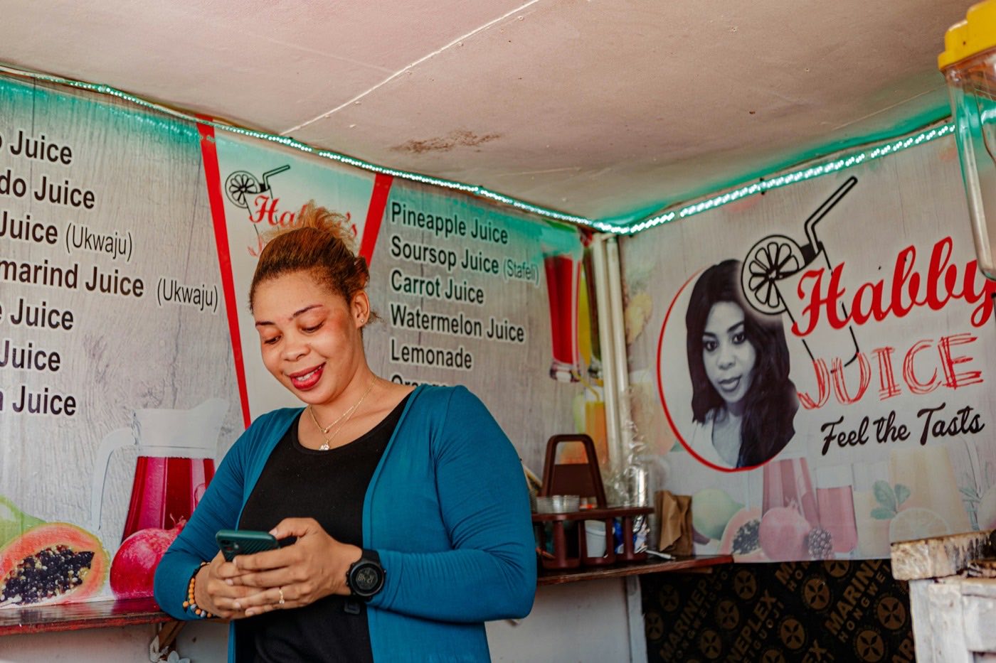 Woman at her juice stand smiling at her phone